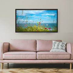 Framed canvas of scenic grass and floral meadow meeting the sea with a black floater frame, ideal for modern and relaxing wall spaces