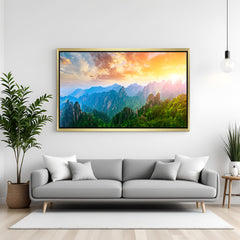 Glowing sunrise canvas print with rainbow-style sunlight over hills and mountains, displayed in golden floater frame for warm and peaceful home decor